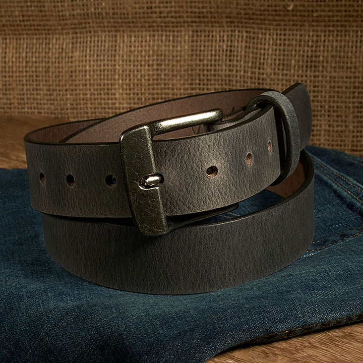 Brown leather belt with a metal buckle on a denim surface