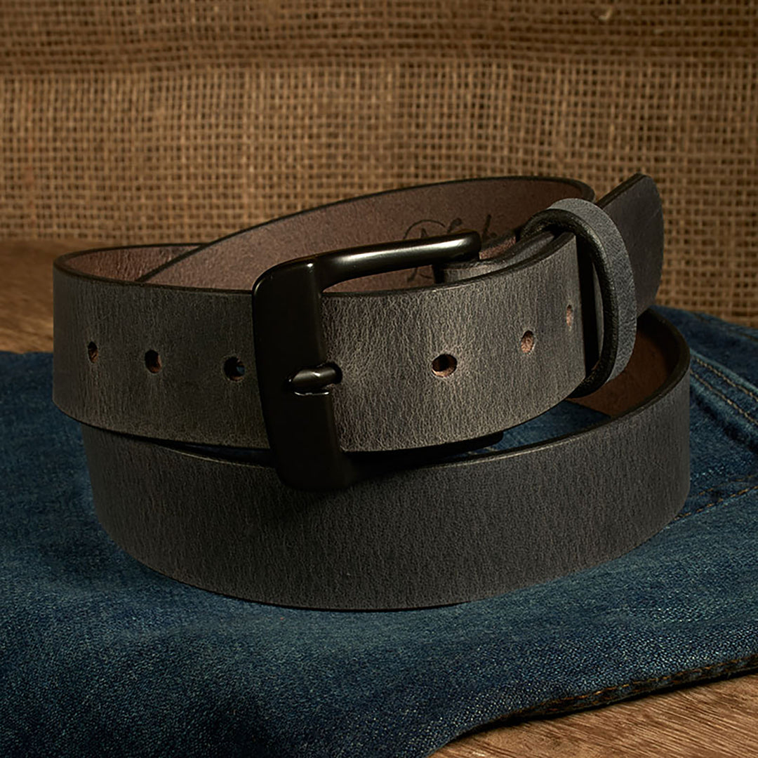 Dark brown leather belt with a black buckle on a denim surface.