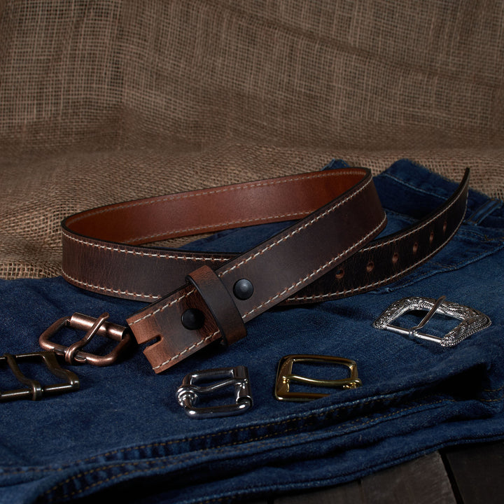 Brown leather belt with various metal buckles on a textured brown background