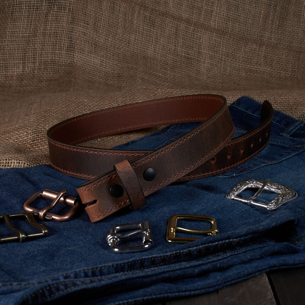 Brown leather belt with various metal buckles on a denim surface