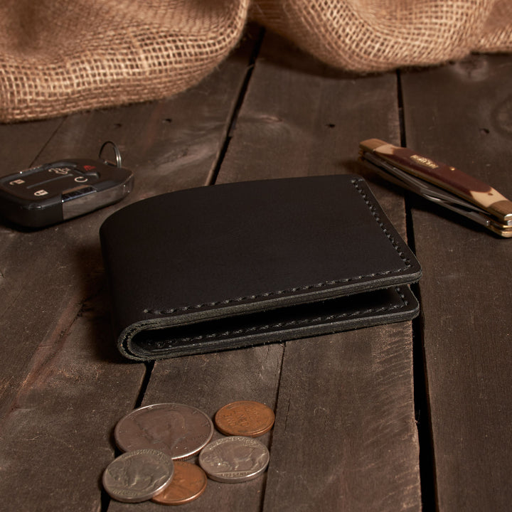Black leather wallet with coins on a wooden surface