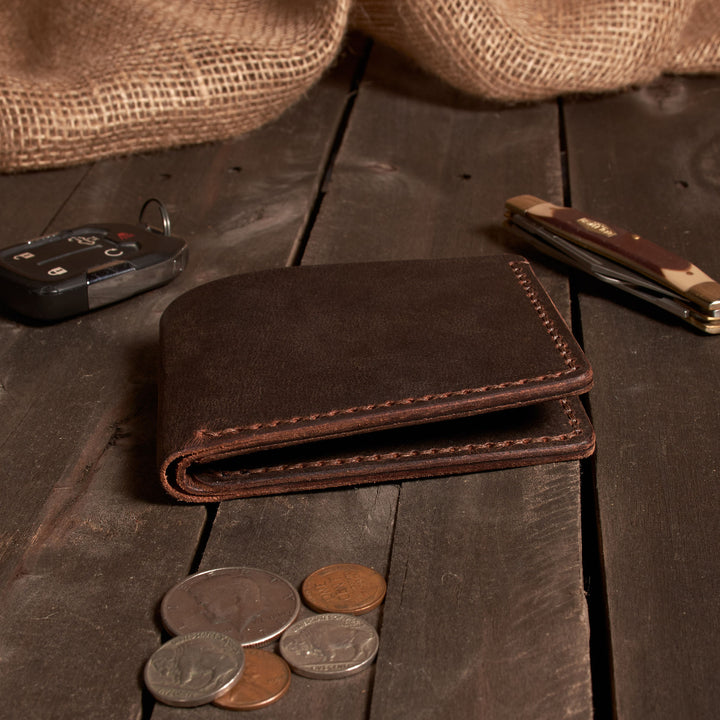 Brown leather wallet with coins on a wooden surface