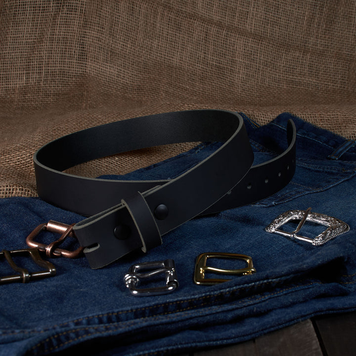 Black belt with various metal buckles on a denim fabric background