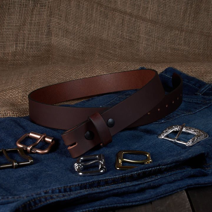 Brown leather belt with various metal buckles on a textured fabric background
