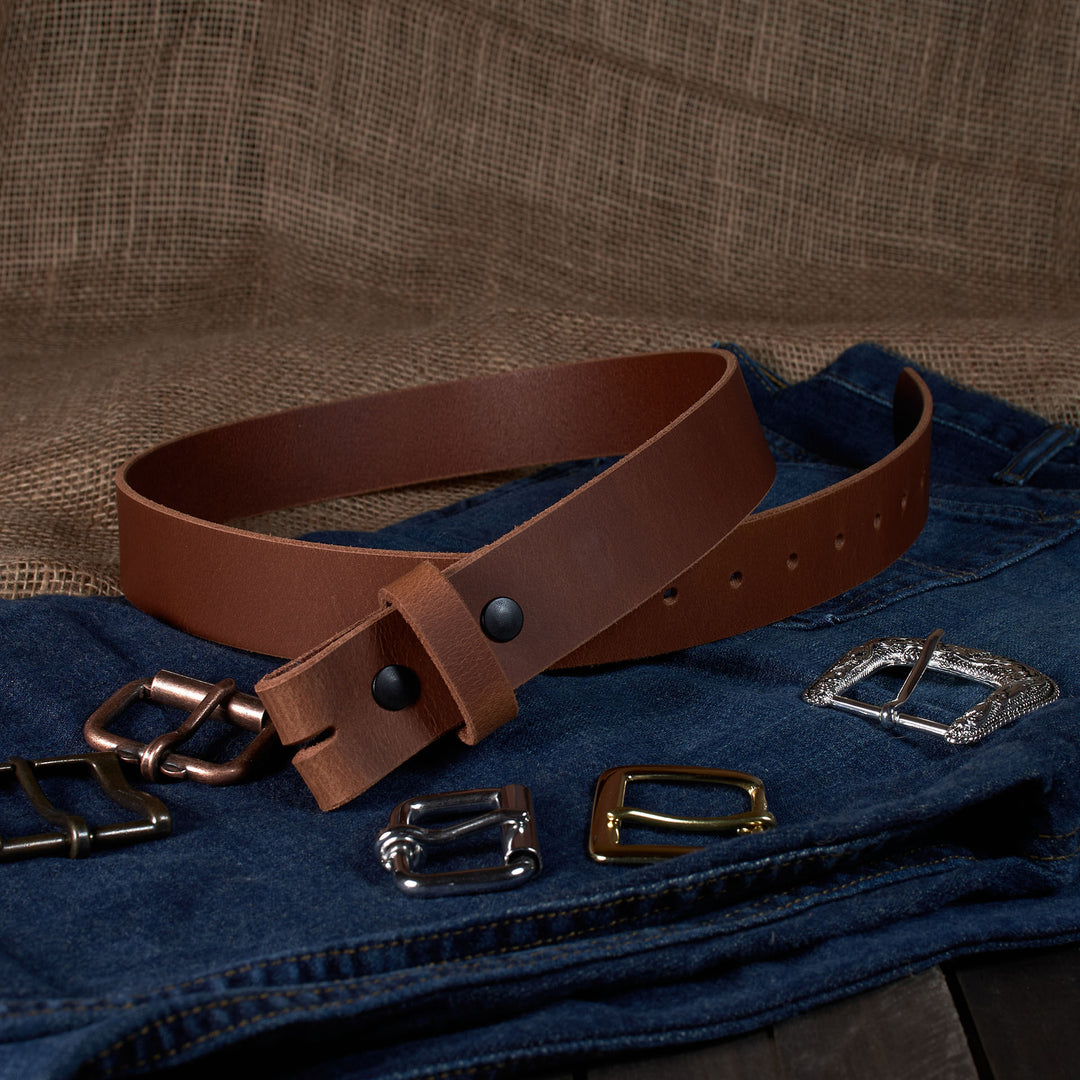 Brown leather belt with various metal buckles on a denim fabric background