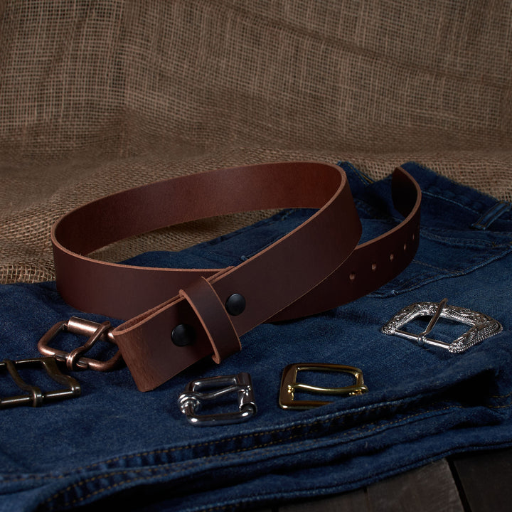 Brown leather belt with various metal buckles on a textured fabric background