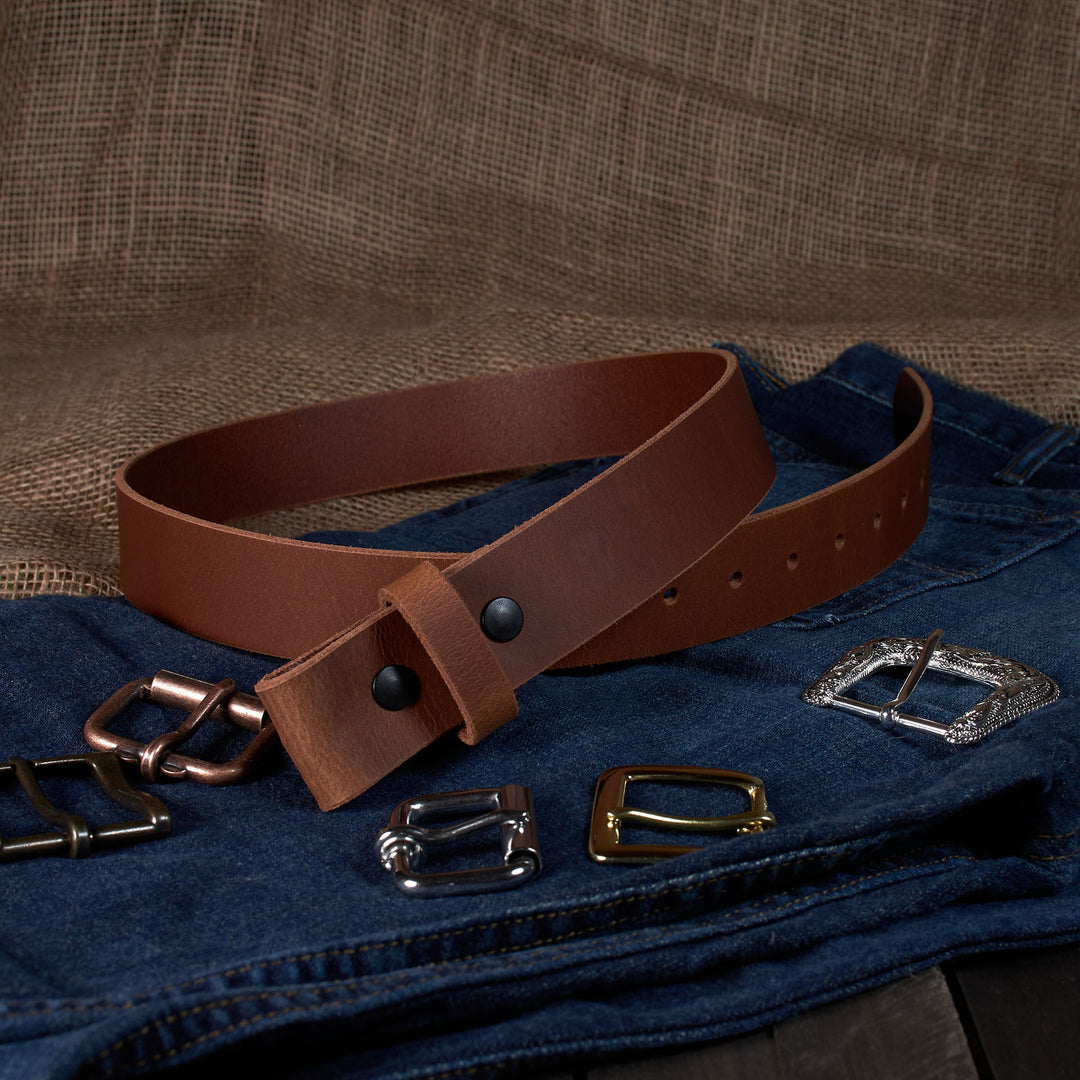 Brown leather belt with various metal buckles on a denim fabric background