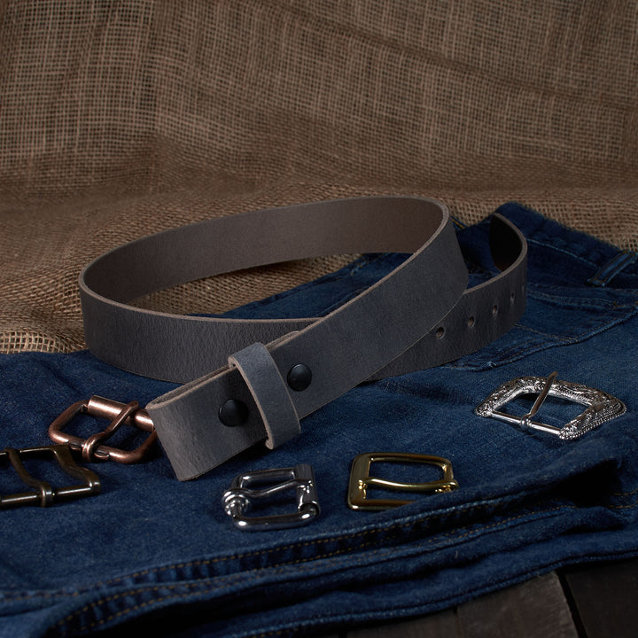 Gray leather belt with various metal buckles on a denim surface