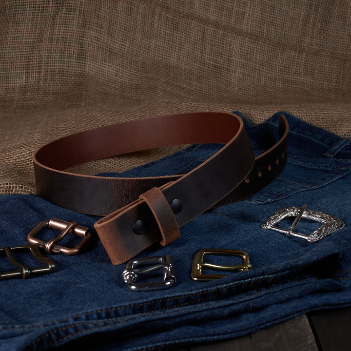 Brown leather belt with various metal buckles on a textured brown background