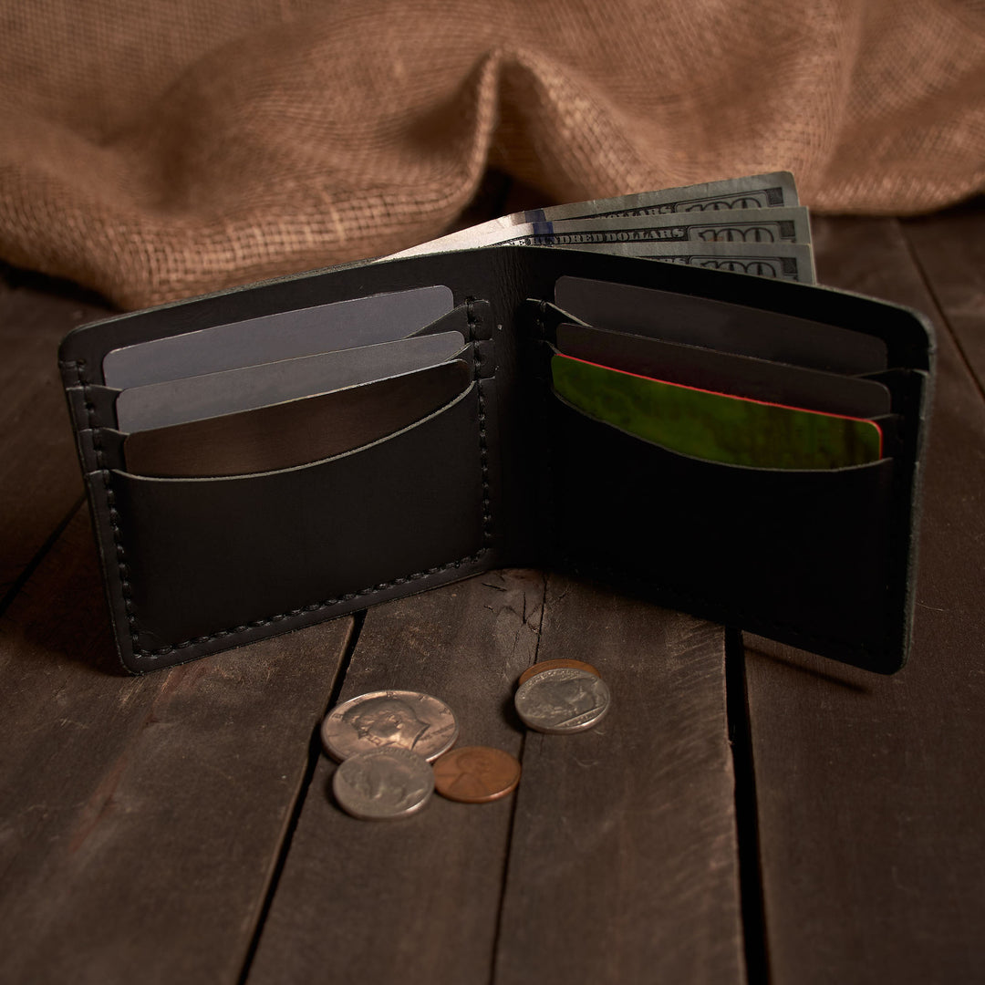 Black leather wallet with money and coins on a wooden surface