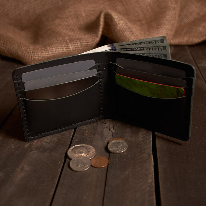 Black leather wallet with money and coins on a wooden surface