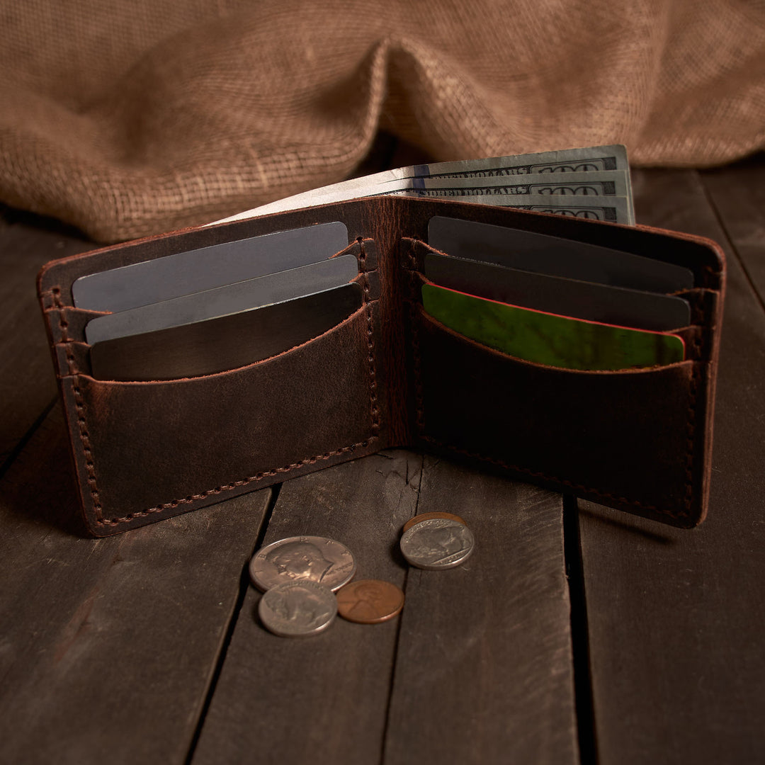 Open brown leather wallet with money and coins on a wooden surface