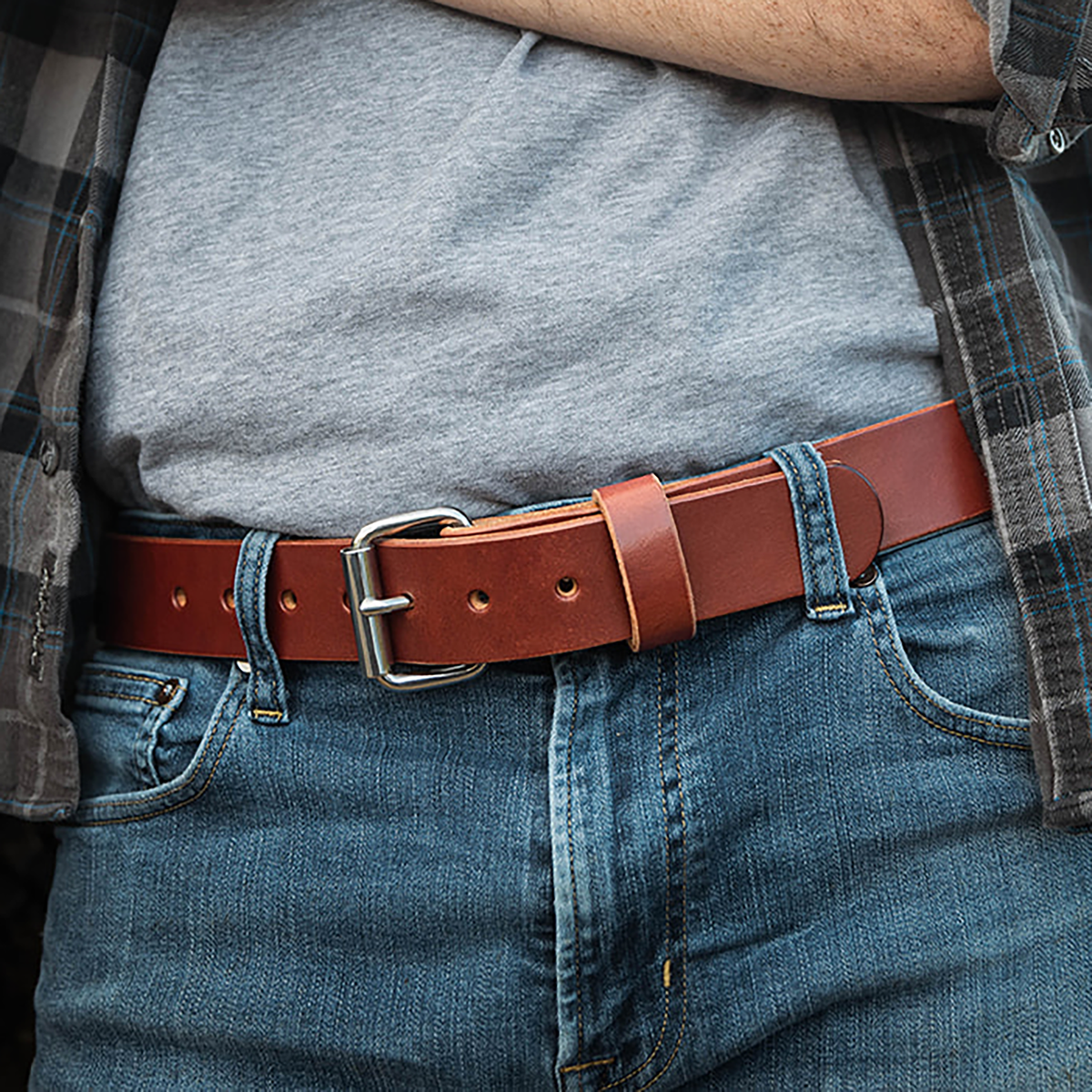 Person wearing a brown leather belt with a plaid shirt and gray shirt.