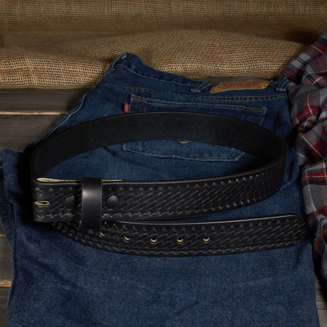Black leather belt on a blue denim jacket with a plaid shirt in the background.
