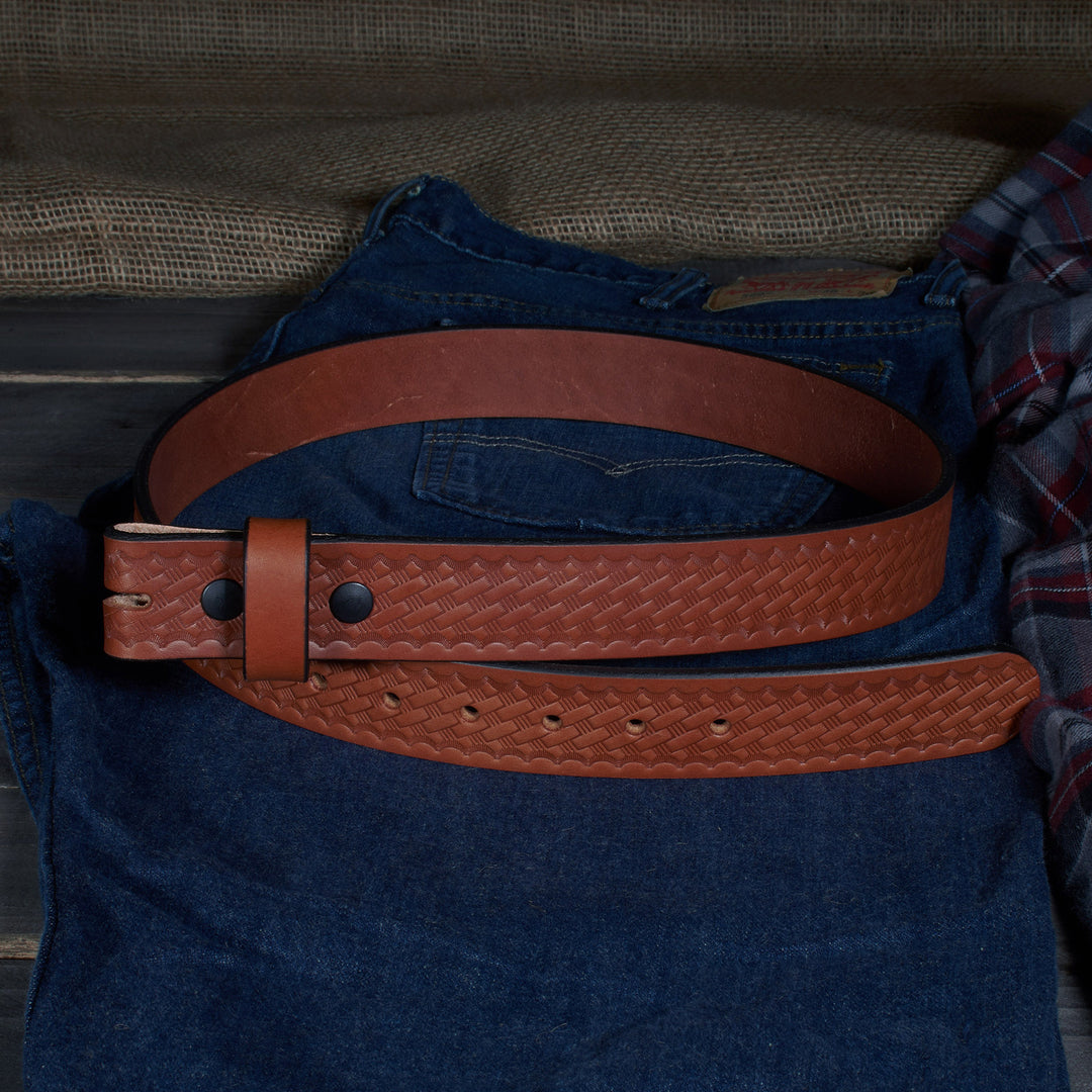 Brown leather belt on a blue denim shirt with a plaid shirt underneath, against a wooden surface.