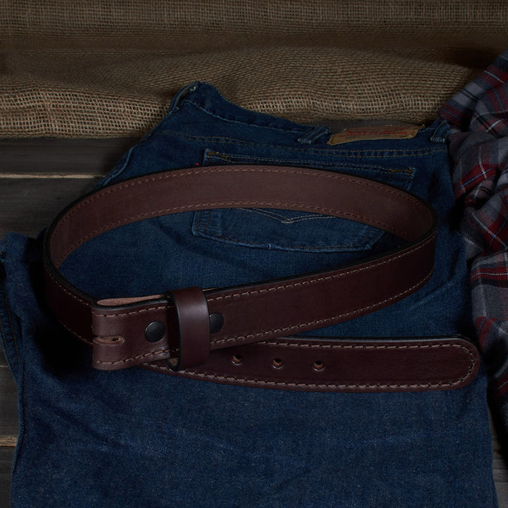 Brown leather belt on a blue denim shirt with a wooden surface in the background