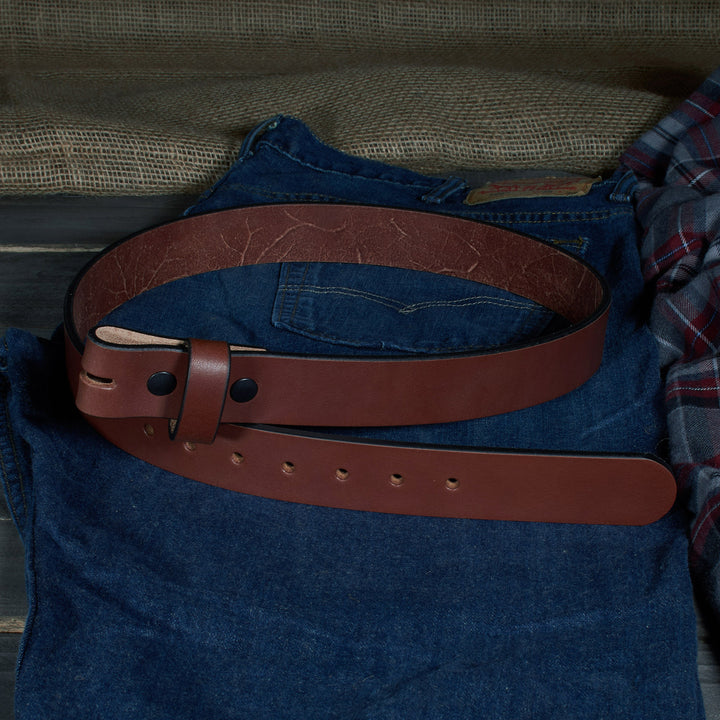 Brown leather belt on a blue denim shirt with plaid fabric in the background