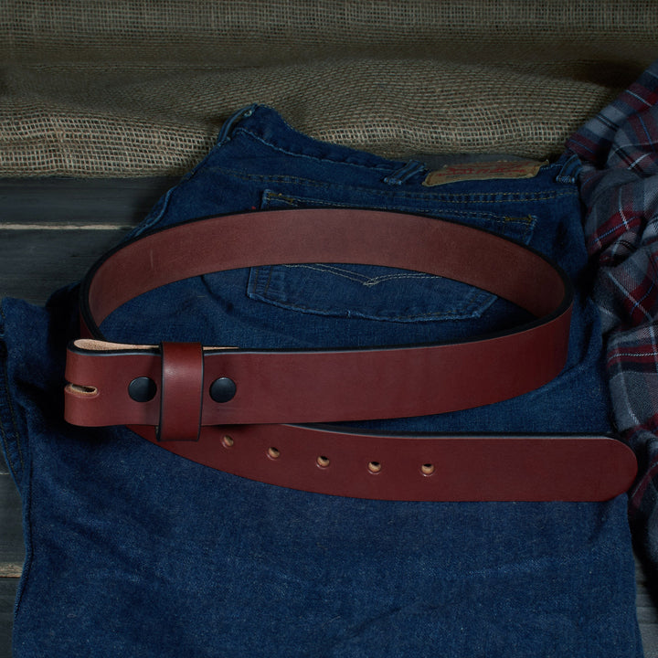 Brown leather belt on a blue denim jacket with a plaid shirt in the background.