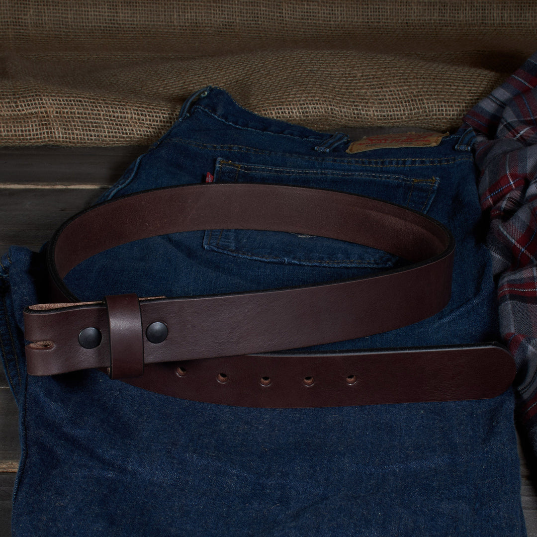 Brown leather belt on blue jeans with a plaid shirt in the background