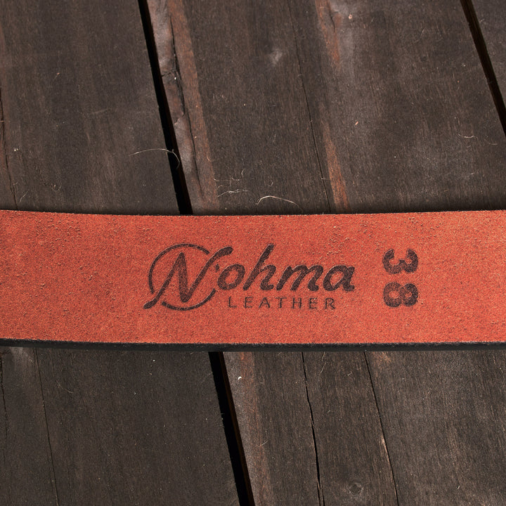 Red leather strap with 'Nohma Leather' branding on a wooden background