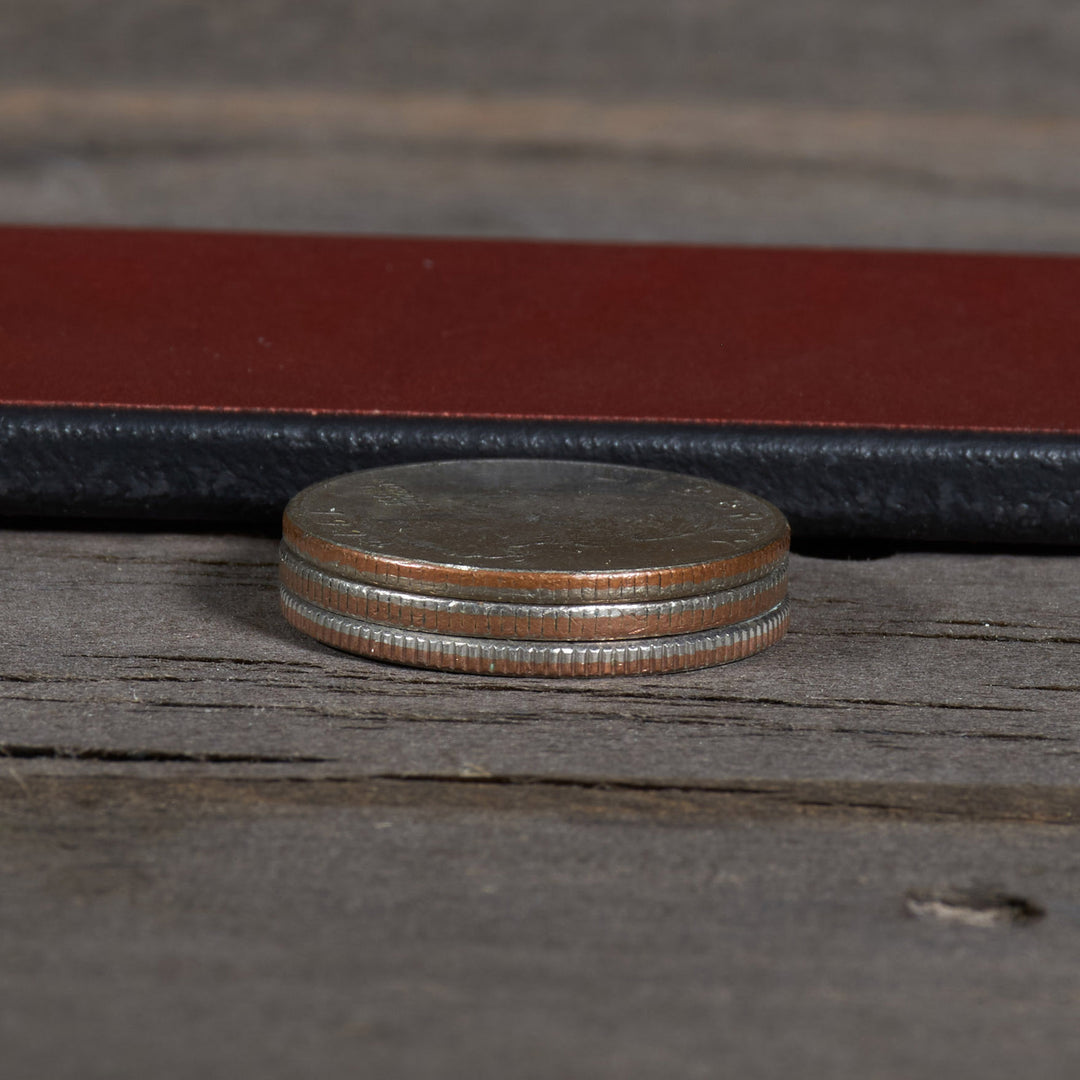 Stack of coins on a wooden surface with a leather-bound book in the background