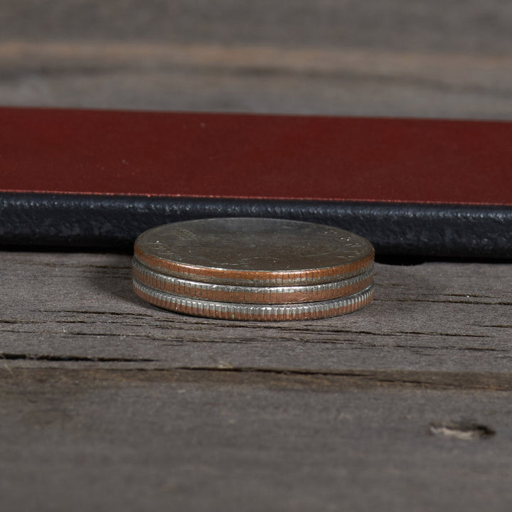 Stack of coins on a wooden surface with a leather-bound book in the background