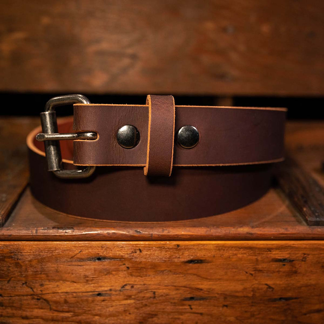 Brown leather belt laying top of a workbench